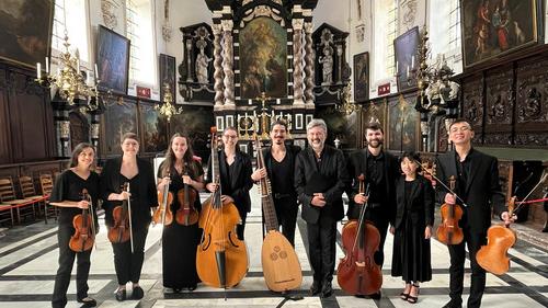 A group photo inside an ornate church of the student and alum players holding their instruments